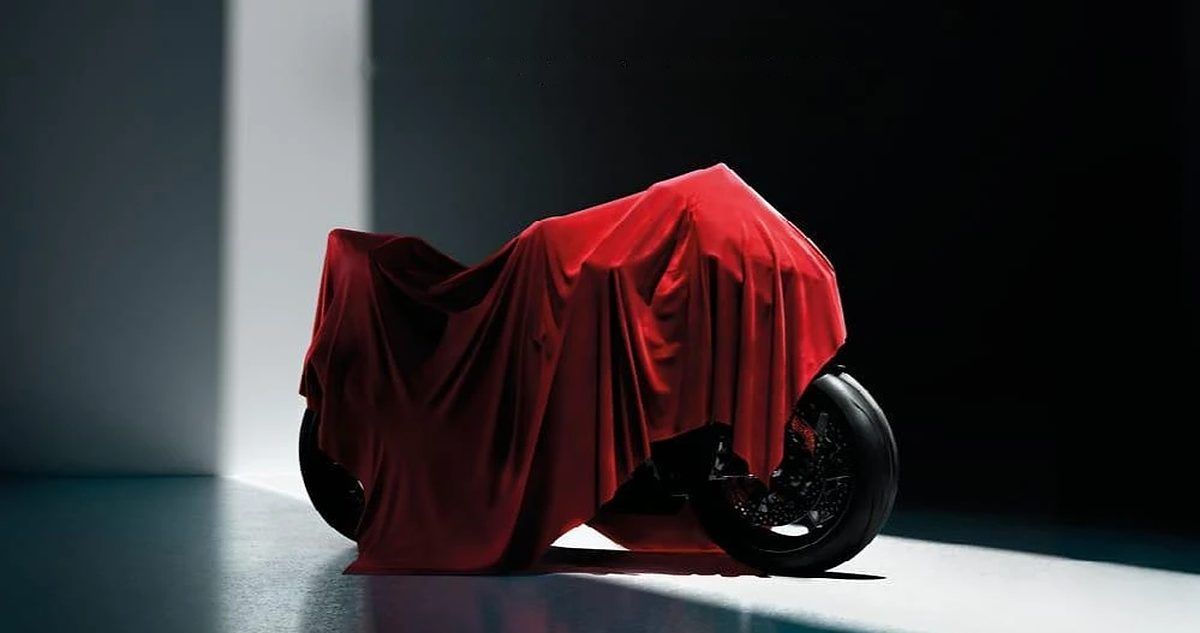 Official EICMA 2026 key visual showing a motorcycle hidden under a red cover in a dark studio