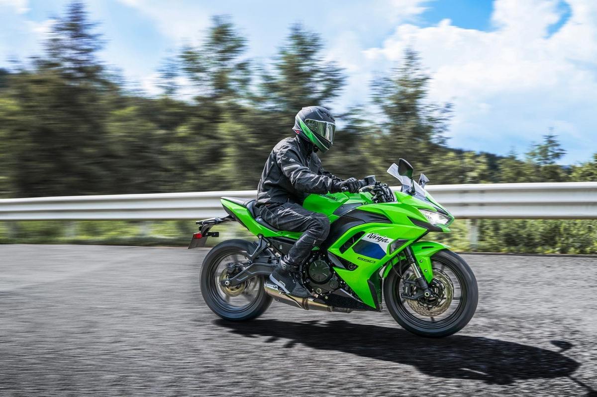 2027 Kawasaki Ninja 650 ABS in Lime Green with rider on a sunny mountain road, right-to-left action shot