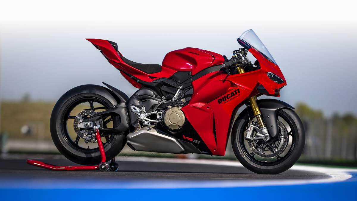 Ducati Red 2027 Ducati Panigale V4 S superbike in right-side profile on a red paddock stand at a racetrack, with gold öhlins fork and V4 S fairing decal